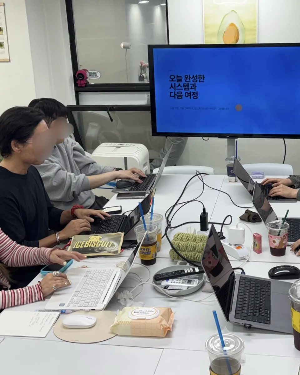 공개 강의 현장 — 참가자들이 노트북으로 실습하고, 화면에 '오늘 완성한 시스템과 다음 여정'이 떠 있다. 얼굴은 흐림 처리